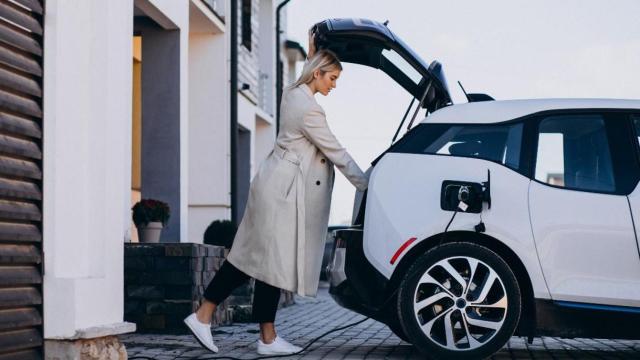 Una mujer carga su coche eléctrico / FREEPIK