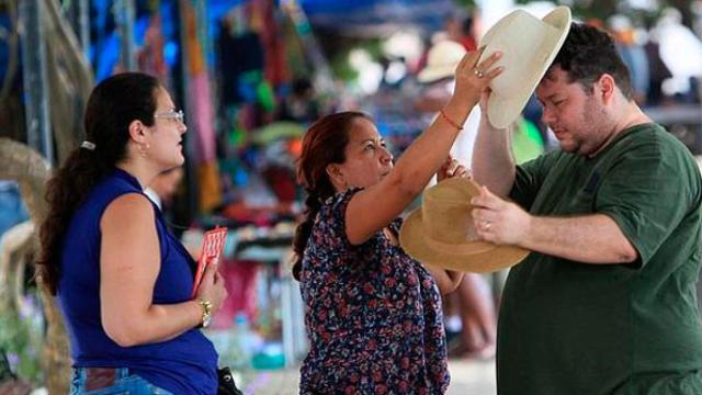 Tres turistas extranjeros se prueban sombreros en una calle en España / EFE