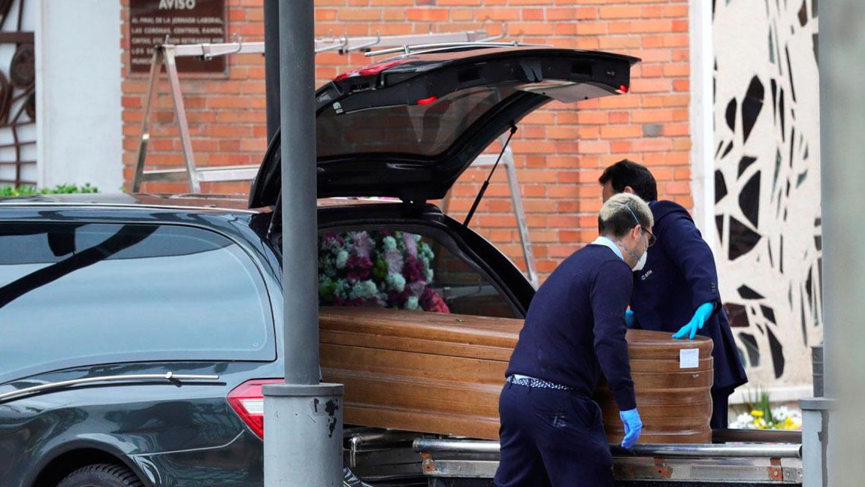 Dos funerarios colocan un féretro en un coche fúnebre en Madrid en plena pandemia / EFE