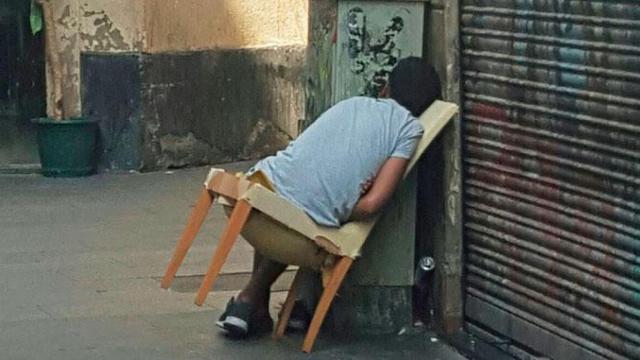 Una persona, durmiendo en una silla abandonada en el Raval / CG