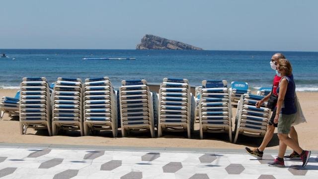 Dos personas pasean por el paseo marítimo de una playa / EFE