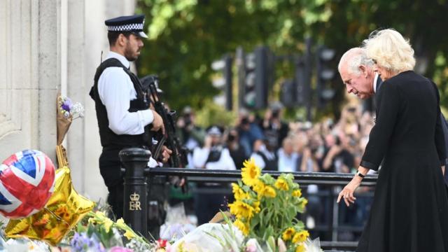 El rey Carlos III y Camilla, la reina consorte, observan los tributos florales a su llegada al Palacio de Buckingham en Londres / EFE