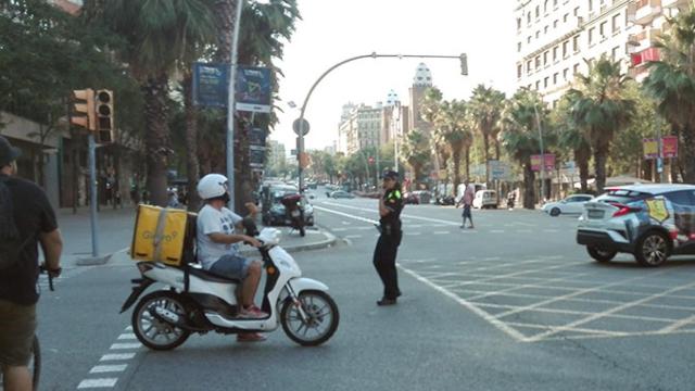 Una agente de policía dirige el tráfico junto a un semáforo apagado durante el corte de luz del 31 de julio en el cruce Casp y Marina de Barcelona / CG