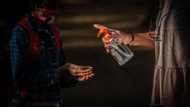 Una profesora administra gel desinfectante a un alumno en un colegio de Cataluña / EP