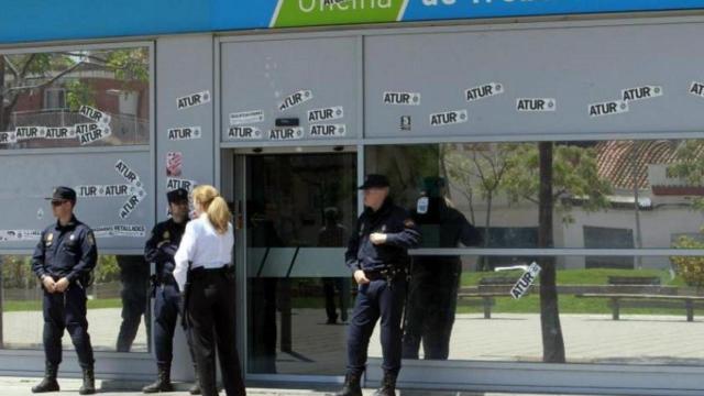 Oficina de empleo de Cataluña con diversas etiquetas con la palabra 'paro' enganchadas en sus cristales / EFE