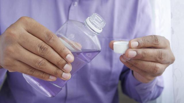 Un hombre sostiene un bote de enjuague bucal /PEXELS