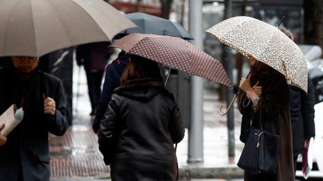 Transeúntes de Barcelona con un paraguas se protegen de la lluvia / EFE