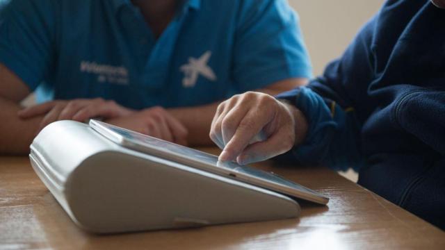 Voluntaria de La Caixa enseña a una persona el uso de tablets para comunicarse con sus familiares /LA CAIXA