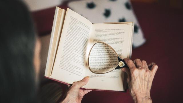 Una persona mayor lee un libro con una lupa / ARCHIVO