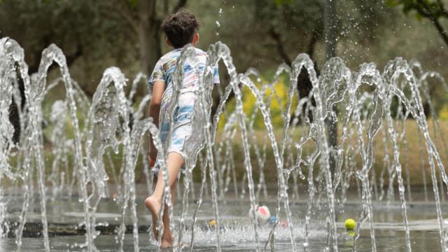 Un niño se moja en unos chorros durante la ola de calor / EUROPAPRESS