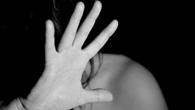 Una mujer protege su rostro contra una agresión machista