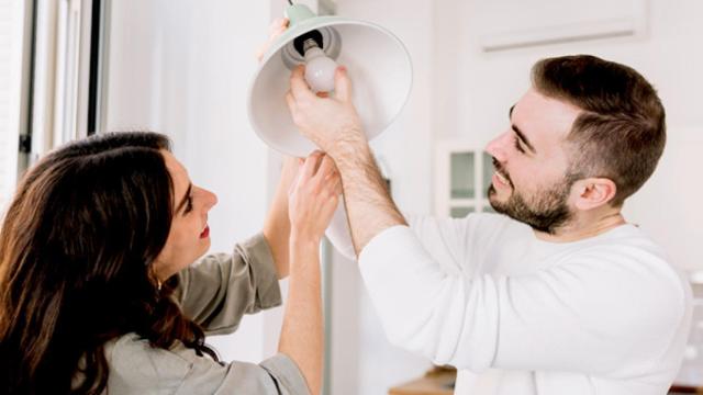 Una pareja cambiando una bombilla por una de bajo consumo / CG