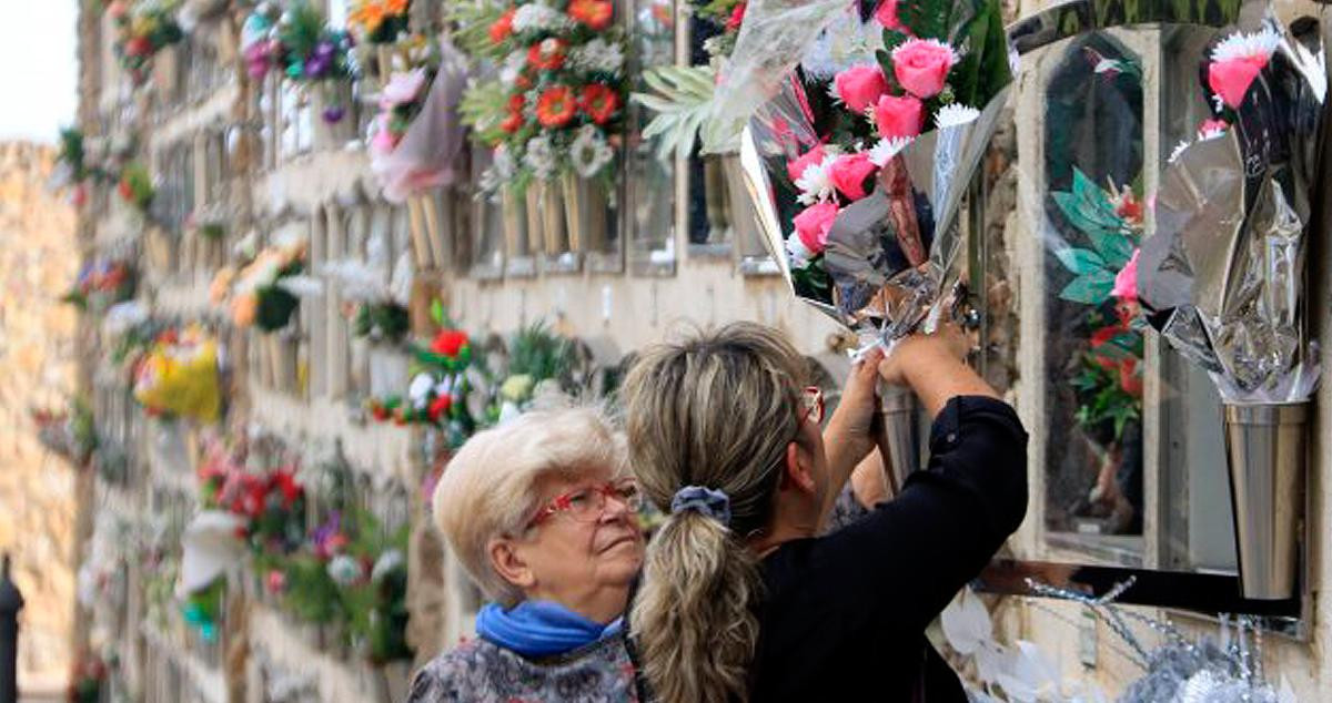 Dos usuarias dejan flores en la sepultura de un ser querido en un cementerio de Barcelona / CG