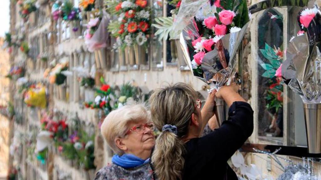 Dos usuarias dejan flores en la sepultura de un ser querido en un cementerio de Barcelona / CG