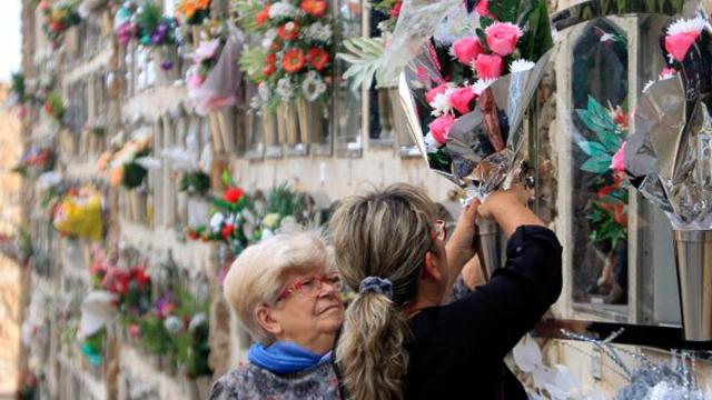 Dos usuarias dejan flores en la sepultura de un ser querido en un cementerio de Barcelona / CG