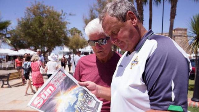 Dos turistas irlandeses leen 'The Sun' en un paseo marítimo de Fuerteventura. La devaluación de la libra 'frena' las reservas hoteleras / EFE