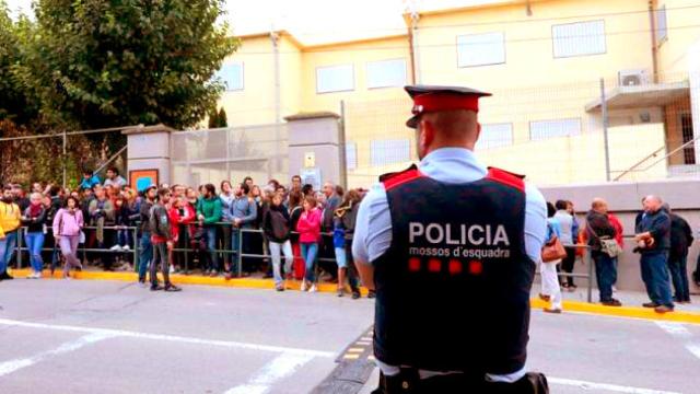 Decenas de personas hacen cola desde las 5 de la mañana en el IES Montbui ante la mirada de un mosso / EFE