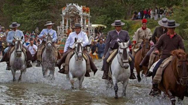 Un grupo de peregrinos cruzan un río a caballo, camino del Rocío / EFE