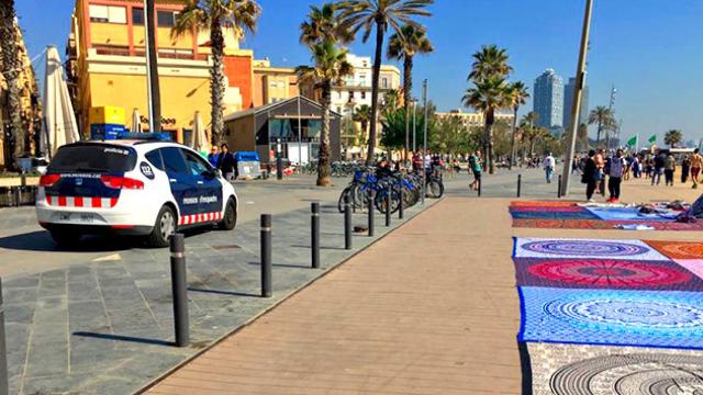 Una patrulla de Mossos d'Esquadra, frente a un grupo de 'manteros' en la playa de Barcelona / CG