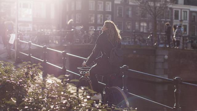 Una turista paseando en bicicleta por Ámsterdam / GENERATOR HOSTELS