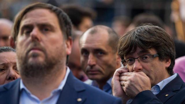 Carles Puigdemont, expresidente catalán, habla discretamente por el móvil detrás de Oriol Junqueras (ERC) / EFE