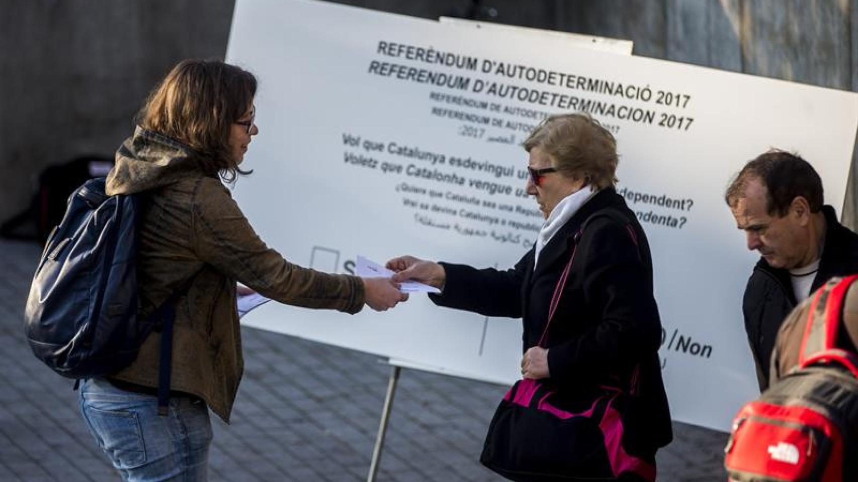 La diputada de la CUP, Eulàlia Reguant (c), reparte papeletas en el centro de Barcelona en el marco de una campaña en que la CUP ha repartido en diferentes puntos de Cataluña 250.000 papeletas con su propuesta de pregunta para un eventual referéndum de in