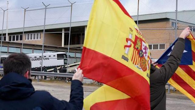 Varios hombres ondean una bandera de España y una estelada a la llegada del autobús de la Guardia Civil con los independentistas presos / EFE