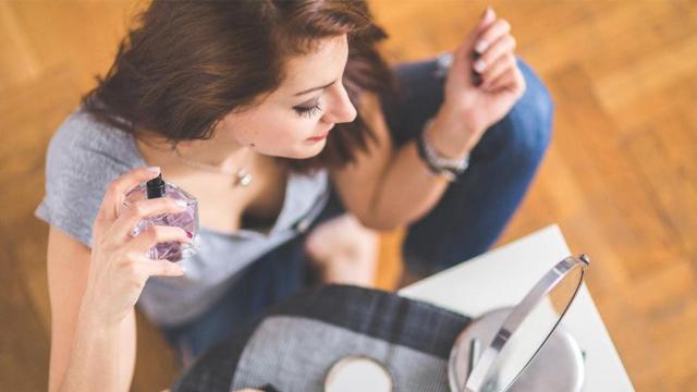 Mujer poniéndose perfume, uno de los productos en los que más se aprecia la tasa rosa / PXHERE