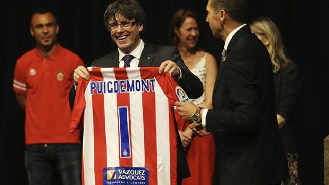 El presidente del Girona FC, Delfí Geli, da una camiseta personalizada al presidente de la Generalitat, Carles Puigdemont, durante la recepción oficial, en el Palau de la Generalitat, al equipo tras subir a primera división / EFE