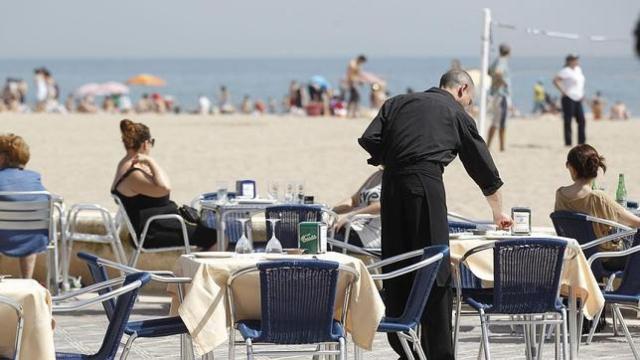 Un camarero sirve las mesas de la terraza de un restaurante en la playa / EFE