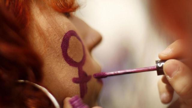 Una mujer siendo maquillada antes de manifestarse / EFE