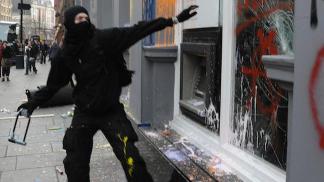 Un radical con la indumentaria black bloc ataca un comercio / CG