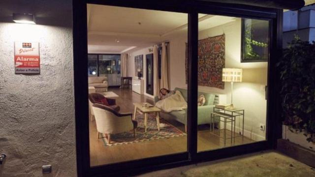 Una mujer descansa en el sofá de su casa protegida con una alarma contra la okupación de viviendas / CG