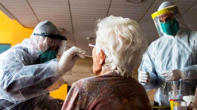 Imagen de dos sanitarios cogiendo muestras a una persona mayor para un test PCR contra el virus / CG