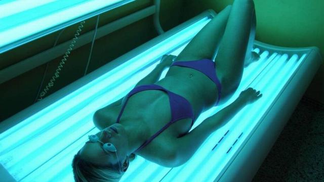 Una mujer dentro de una cabina de bronceado con rayos UVA