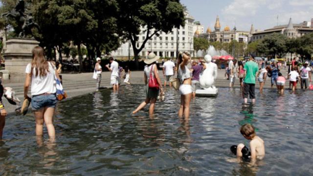 Unos turistas se bañan en la plaza Catalunya de Barcelona durante la ola de calor / CG