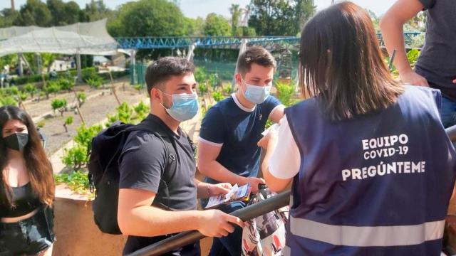 Una informadora contra el Covid-19 atiende a visitantes en la cola de la atracción Furius Baco / CG