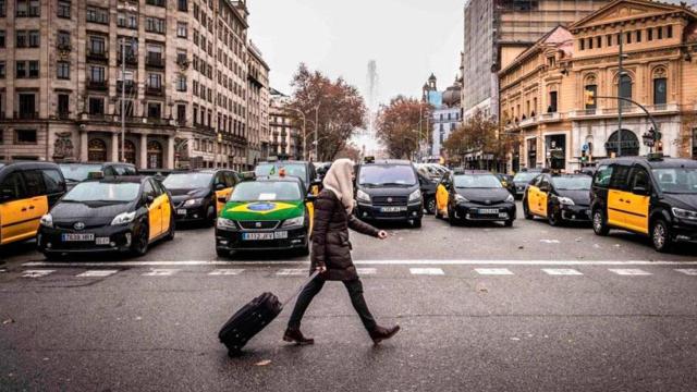 Una ciudadana pasa ante un grupo de taxis durante una protesta en Barcelona / EP