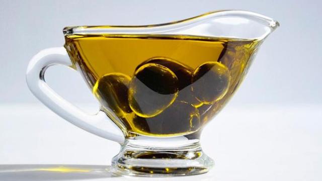 Una taza de aceite de oliva con aceitunas dentro