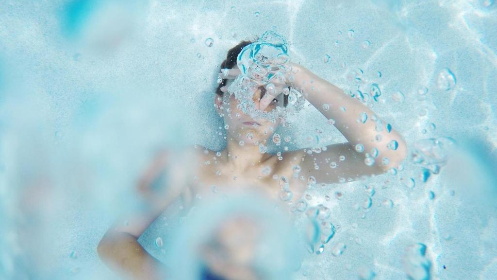 Un menor sumergido en el agua de una piscina