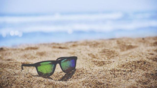Gafas de sol en la arena de una playa / UNSPLASH