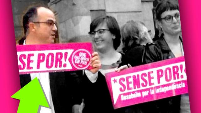 El dirigente de CDC, Jordi Turull, dobla una pancarta para esconder un lema sobre la desobediencia en una concentración / CG