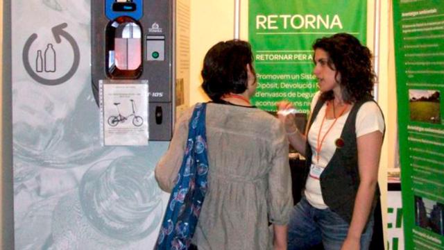 Representantes de la asociación medioambiental Retorna explican el funcionamiento del sistema SDDR. Encima del botón verde se puede ver el nombre de Tomra, el fabricante de la máquina / RETORNA