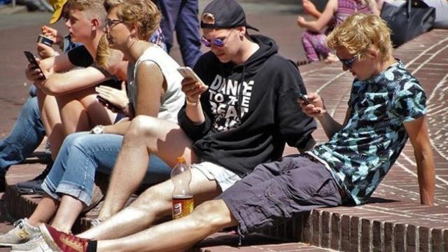 Jóvenes navegan con sus móviles en las redes sociales