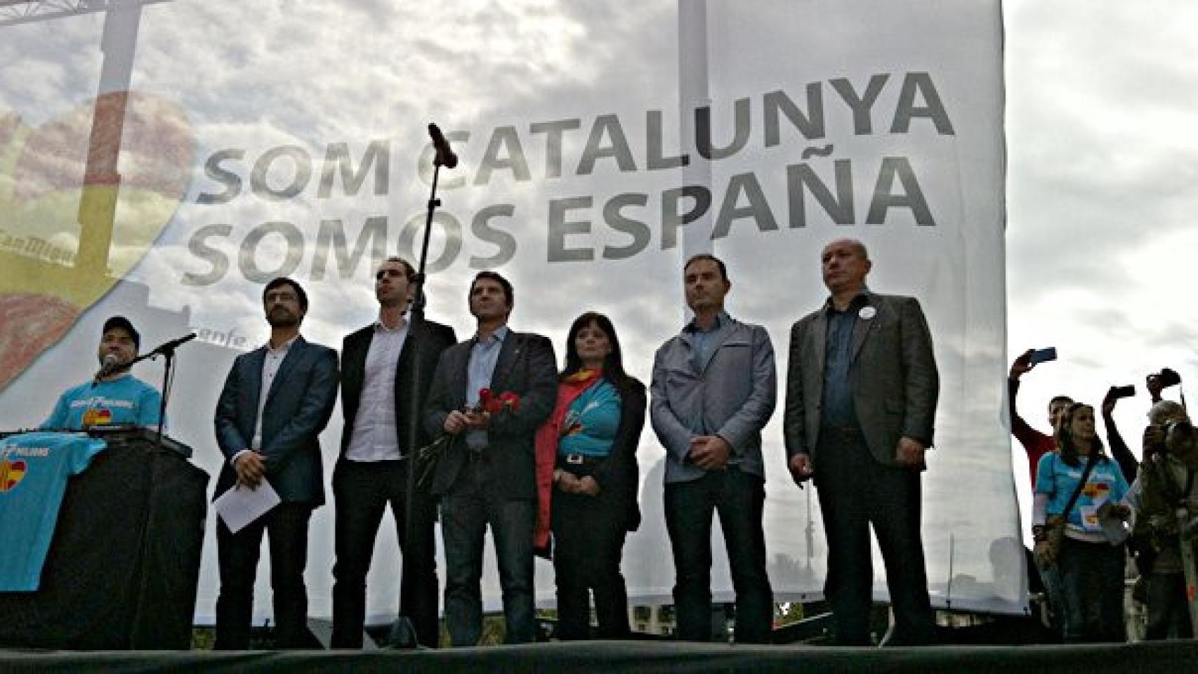 Los portavoces de Som Catalunya. Somos España, en el escenario del acto del 12-O, mientras suena el himno nacional