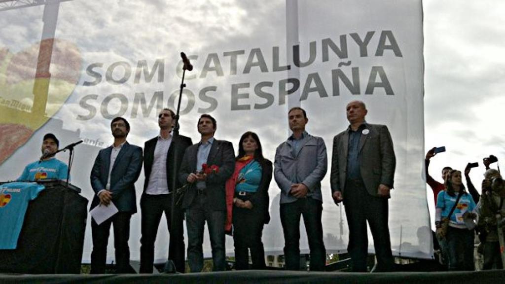 Los portavoces de Som Catalunya. Somos España, en el escenario del acto del 12-O, mientras suena el himno nacional
