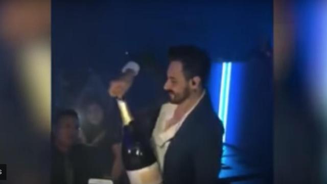 El hombre mientras abre la botella de champán