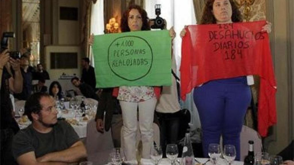 Dos activistas de la PAH, junto al diputado autonómico de la CUP David Fernández, en el míting del candidato del PP, Miguel Arias Cañete