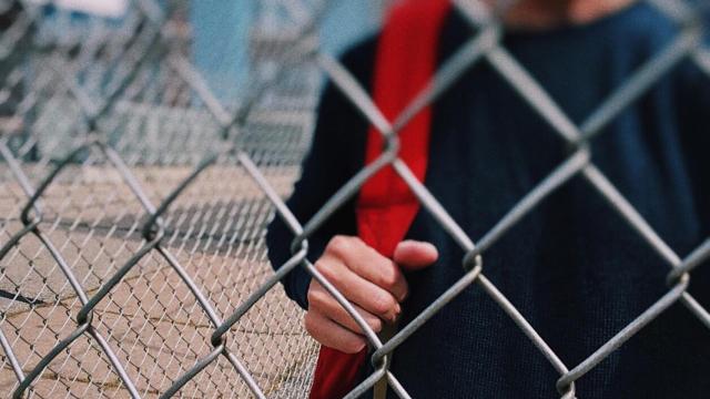 Un alumno de secundaria detrás de las verjas de un instituto/ PIXABAY