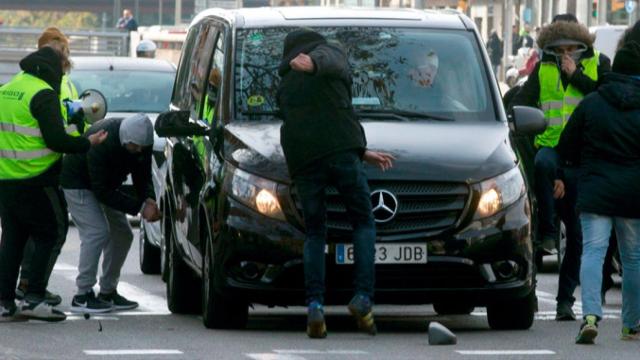 Taxistas de Barcelona atacando un vehículo VTC, como los que utilizan Uber y Cabify, ayer / EFE
